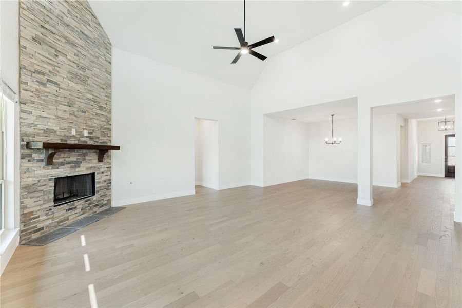 Open living room with vaulted ceiling, stacked stone fireplace, and hardwood floors Open living room with vaulted ceiling, stacked stone fireplace, and hardwood floors