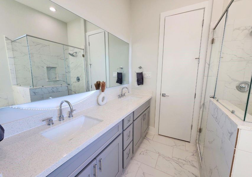 This bathroom features a modern design with a double vanity, sleek fixtures, a spacious glass-enclosed shower, and elegant marble-style tiles. Ideal for a stylish, functional space. This bathroom features a modern design with a double vanity, sleek fixtures, a spacious glass-enclosed shower, and elegant marble-style tiles. Ideal for a stylish, functional space.