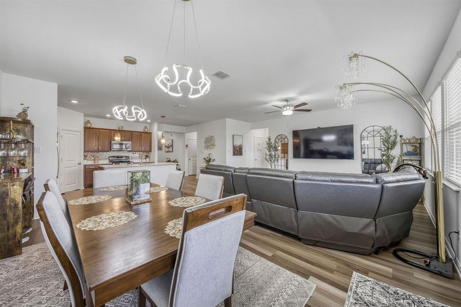 Open-concept dining area featuring a wood-finish table and contemporary pendant lighting Open-concept dining area featuring a wood-finish table and contemporary pendant lighting