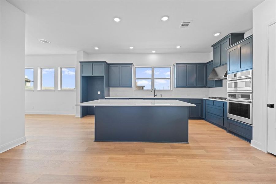 Kitchen with light hardwood / wood-style flooring, a healthy amount of sunlight, and wall chimney exhaust hood