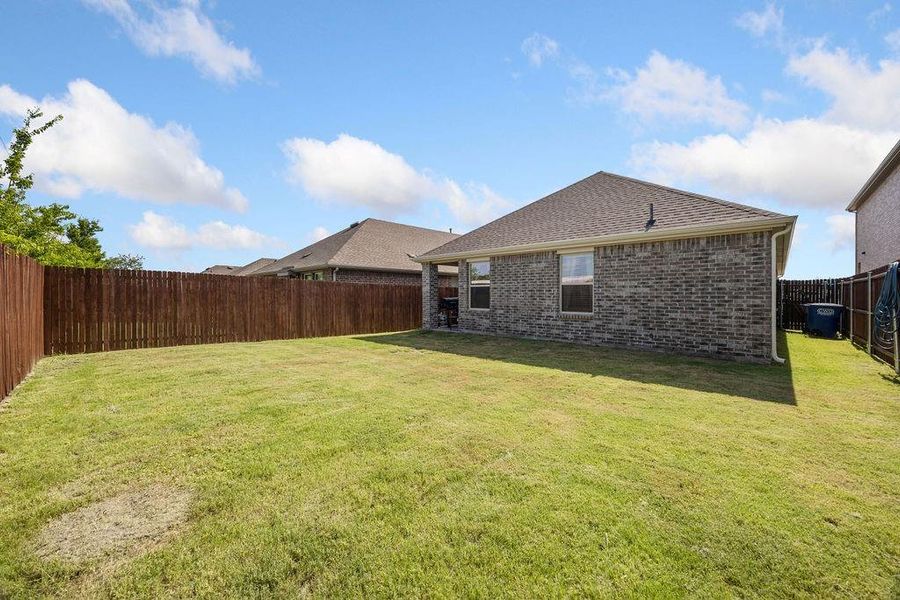 Expansive backyard featuring a manicured lawn, complete wood privacy fencing, and brick exterior Expansive backyard featuring a manicured lawn, complete wood privacy fencing, and brick exterior