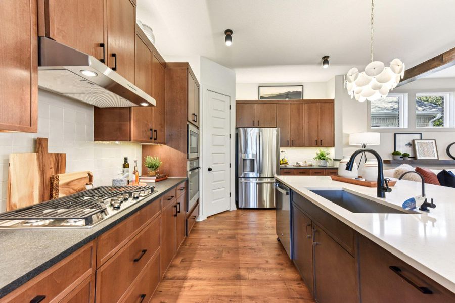 A well-lit kitchen with rich wooden cabinetry, gleaming countertops, and modern stainless steel appliances. A well-lit kitchen with rich wooden cabinetry, gleaming countertops, and modern stainless steel appliances.
