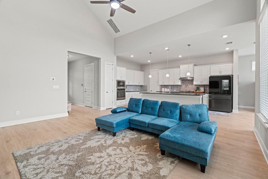 Living room featuring light wood-style floors, high vaulted ceiling, ceiling fan, and recessed lighting Living room featuring light wood-style floors, high vaulted ceiling, ceiling fan, and recessed lighting