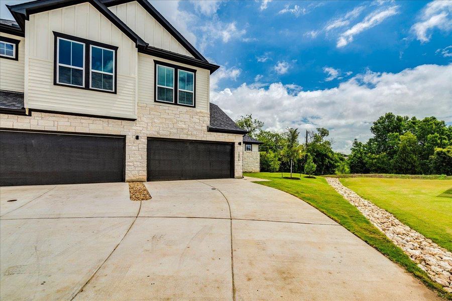 A well-maintained concrete driveway leads to a pristine garage, framed by lush green lawns.