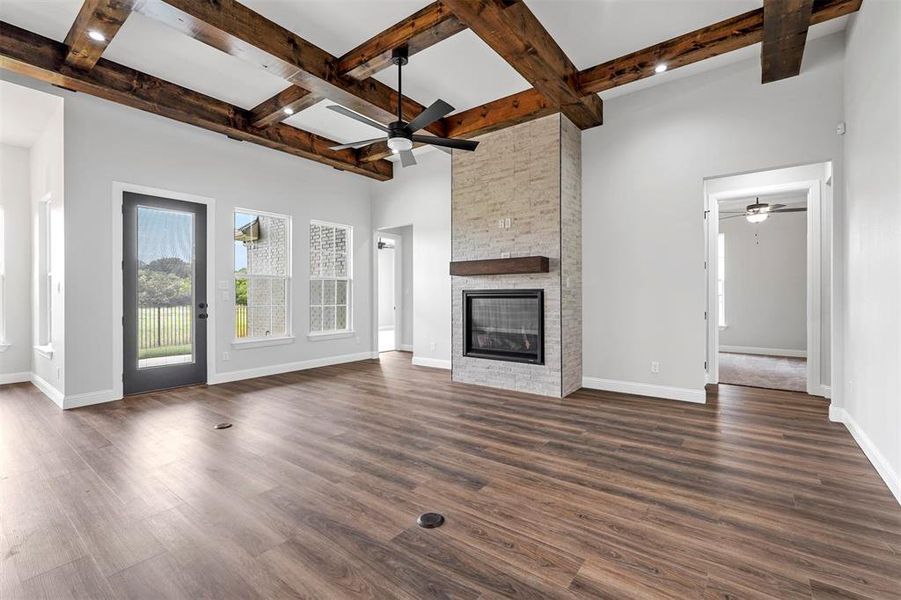 Unfurnished living room featuring beam ceiling, a fireplace, ceiling fan, and dark hardwood / wood-style flooring