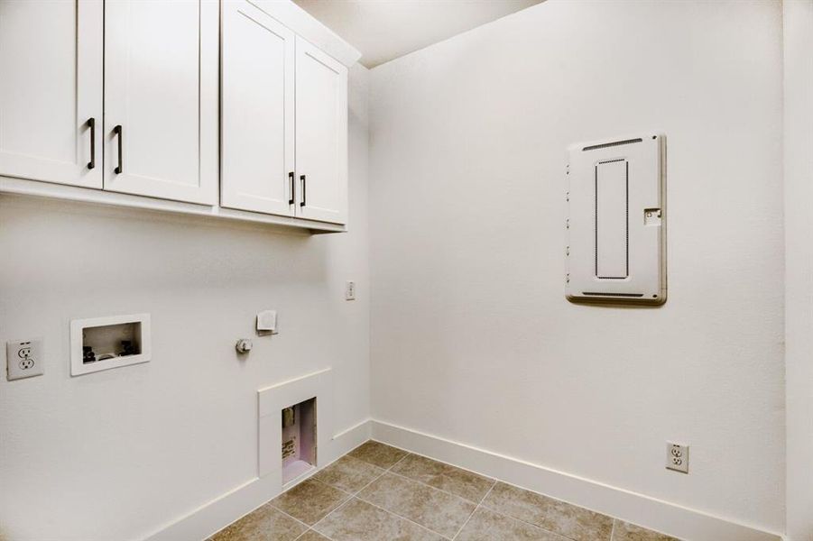 Laundry area with gas dryer hookup, cabinet space, washer hookup, and light tile patterned flooring