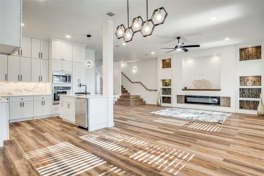 Kitchen featuring open floor plan, white cabinetry, a glass covered fireplace, ceiling fan, and recessed lighting