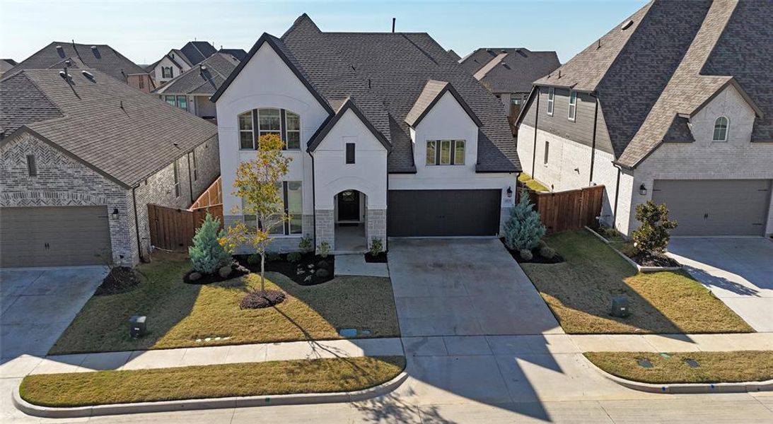 French provincial home with stucco siding, concrete driveway, an attached garage, a residential view, and stone siding