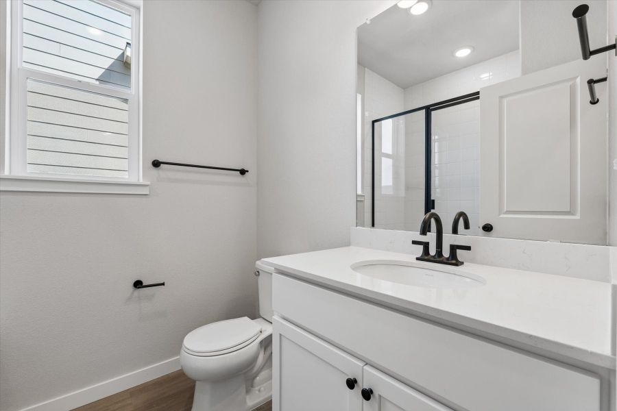 A bathroom with a sink toilet and mirror.