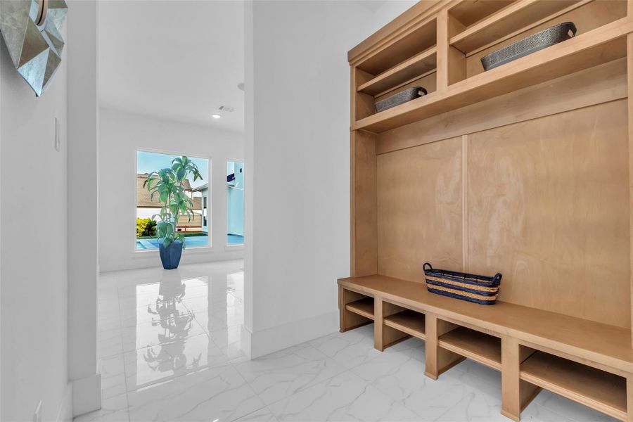 Mudroom (One of Two):One of two thoughtfully designed mudrooms, this space offers custom built-ins and seating with natural light streaming through large windows. Both practical and polished, it ensures effortless organization and a refined transition between indoor living and outdoor leisure.