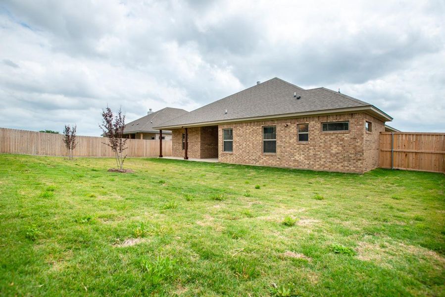 Back of property featuring brick siding, a fenced backyard, and a yard