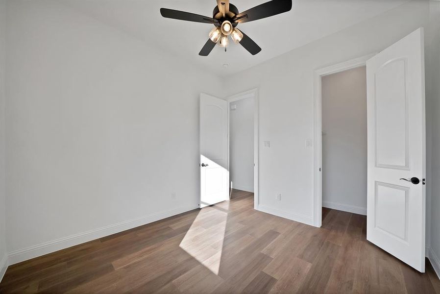Secondary bedroom featuring dark wood finished floors and a ceiling fan