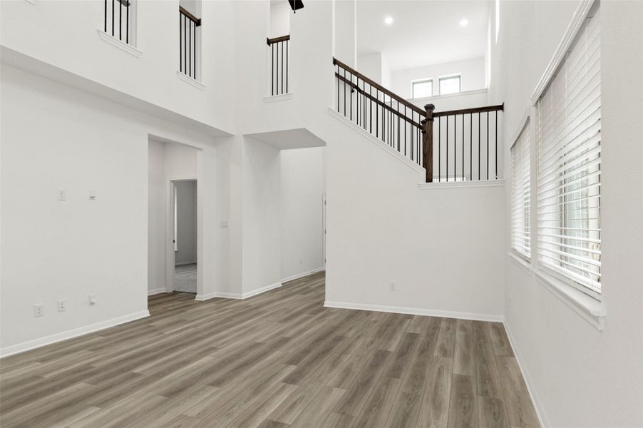 Unfurnished living room featuring wood finished floors, a high ceiling, and stairway