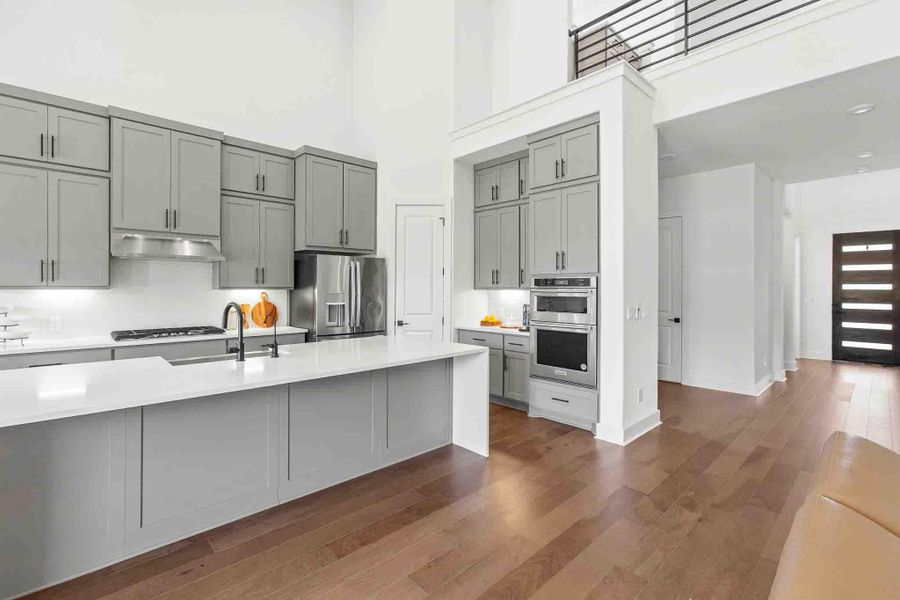 Contemporary kitchen featuring light gray cabinetry, white countertops, and stainless steel appliances