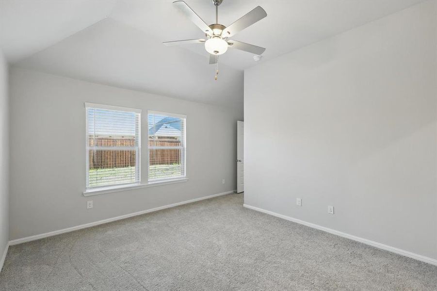 Empty room with carpet floors, vaulted ceiling, and a ceiling fan Empty room with carpet floors, vaulted ceiling, and a ceiling fan