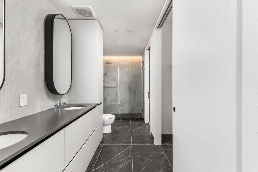 Full bathroom features a sleek double vanity and a spacious glass-enclosed shower.
