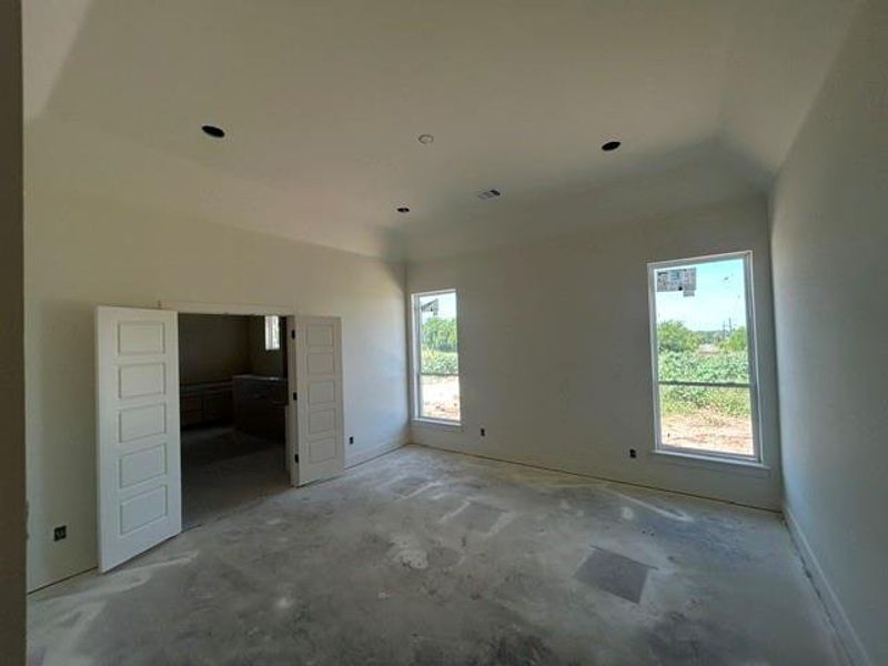 Spacious interior room featuring a vaulted ceiling and recessed lighting