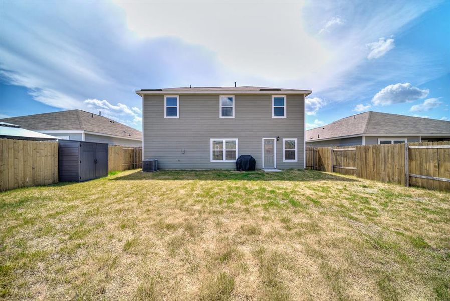 Back of house with a fenced backyard and a storage shed