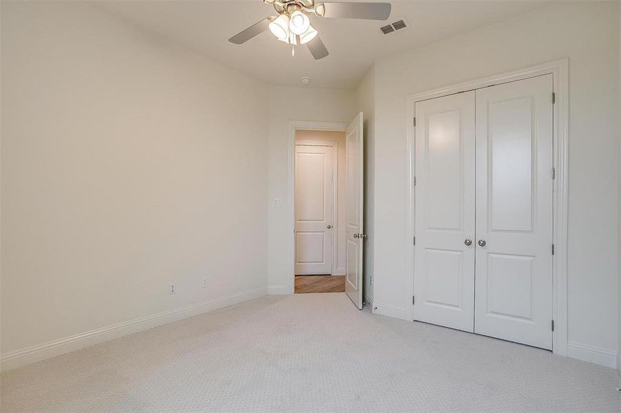 Unfurnished bedroom with ceiling fan, a closet, and light colored carpet