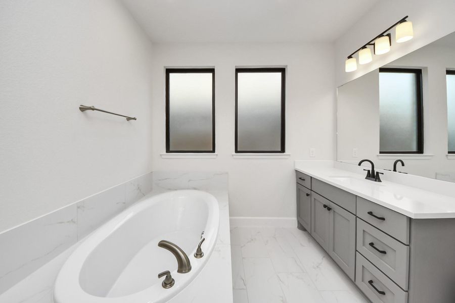 Relaxing soaking tub with oversized windows and extended vanity.