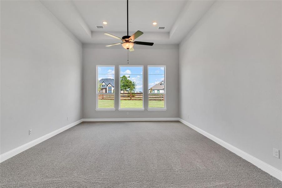 Unfurnished room with ceiling fan, a raised ceiling, and carpet flooring