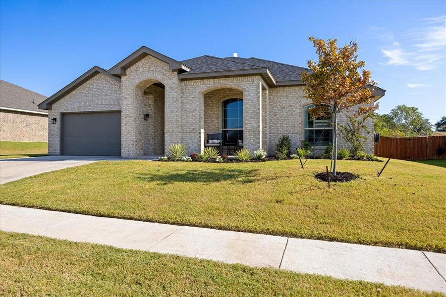 French provincial home featuring brick siding, driveway, an attached garage, and roof with shingles