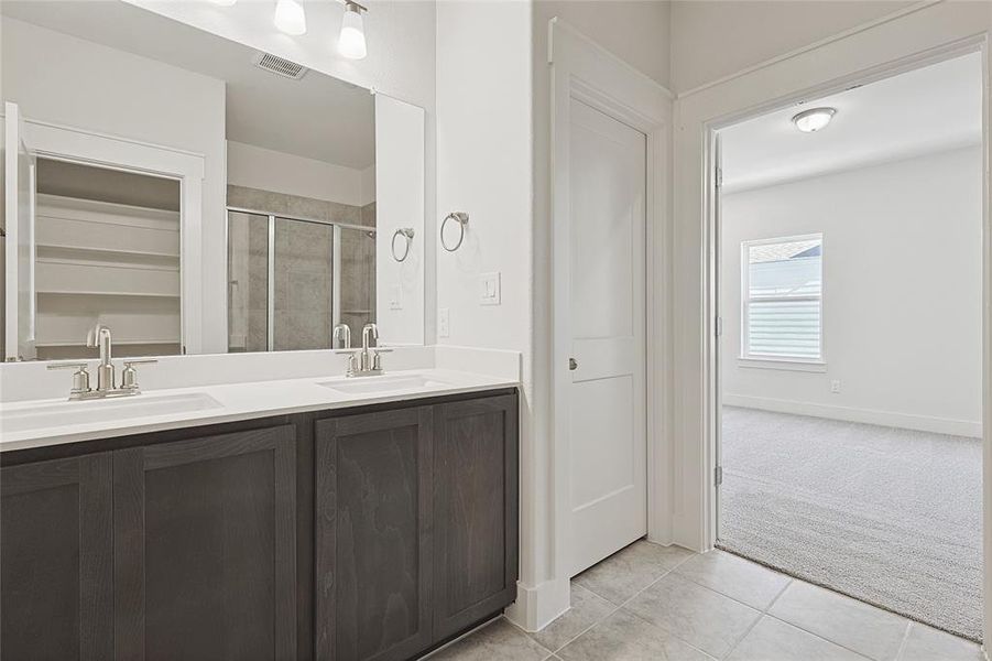 Bathroom featuring tile patterned floors, a shower with door, and vanity