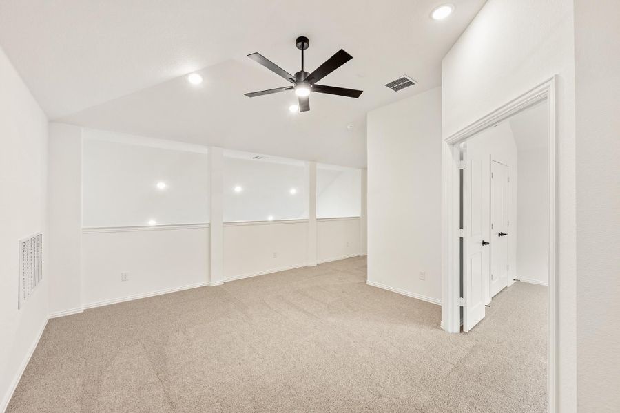 Empty bedroom with vaulted ceiling, ceiling fan, beige carpet, and white walls with two closet doors Empty bedroom with vaulted ceiling, ceiling fan, beige carpet, and white walls with two closet doors