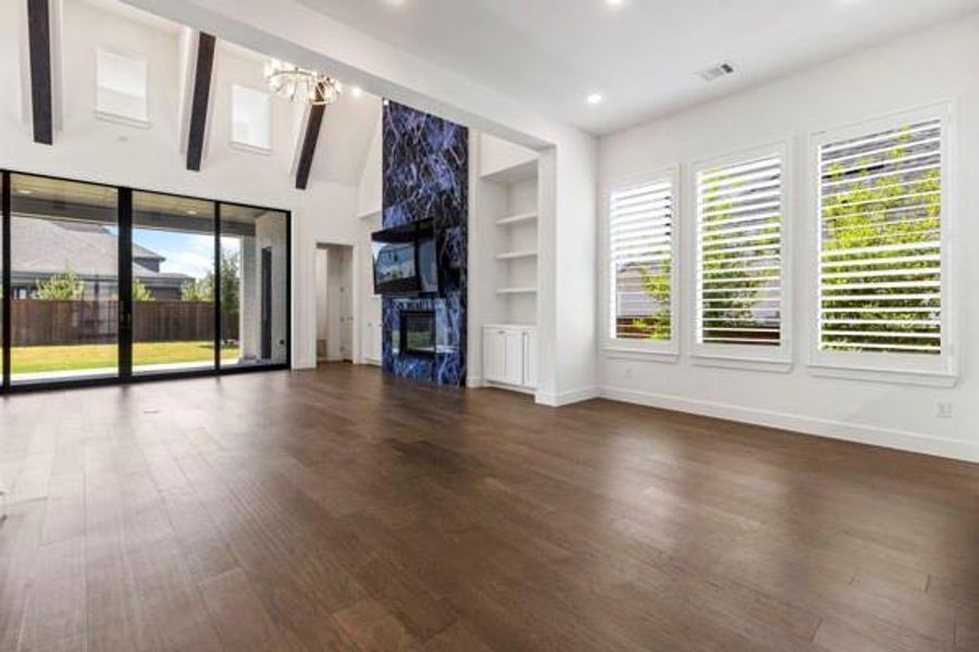 Unfurnished living room with built in shelves, dark wood finished floors, a fireplace, recessed lighting, and a chandelier Unfurnished living room with built in shelves, dark wood finished floors, a fireplace, recessed lighting, and a chandelier