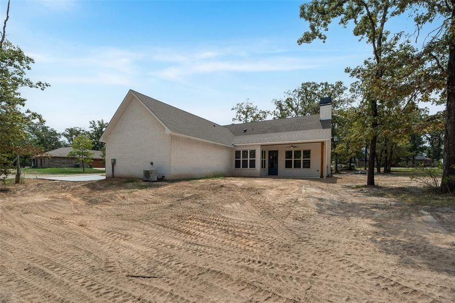 Back of property featuring a chimney, brick siding, and a patio area