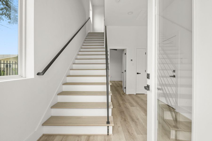 The spacious foyer of the Beckett plan includes recessed lighting, luxury vinyl plank flooring, high ceilings, a convenient furniture nook, entry to the first floor bedroom with ensuite bath, access to the home’s two-car attached garage and a coat closet. The staircase has hardwood treads with modern wrought iron horizontal spindles leading to the second level of the home. The spacious foyer of the Beckett plan includes recessed lighting, luxury vinyl plank flooring, high ceilings, a convenient furniture nook, entry to the first floor bedroom with ensuite bath, access to the home’s two-car attached garage and a coat closet. The staircase has hardwood treads with modern wrought iron horizontal spindles leading to the second level of the home.