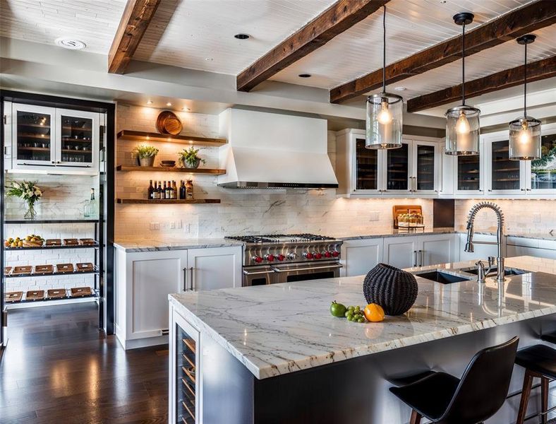 Kitchen with white cabinetry, wall chimney exhaust hood, range with two ovens, decorative backsplash, and light stone countertops