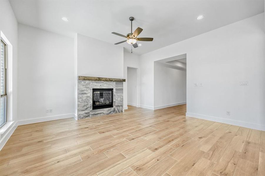 Unfurnished living room with a ceiling fan, recessed lighting, light wood-type flooring, and a fireplace