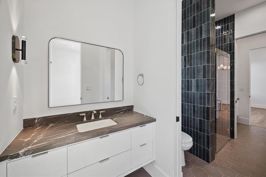 The Hollywood bath is anchored by a stunning walk-in shower featuring mesmerizing blue Zellige tile. Ann Sacks hexagonal tile paves the floors.