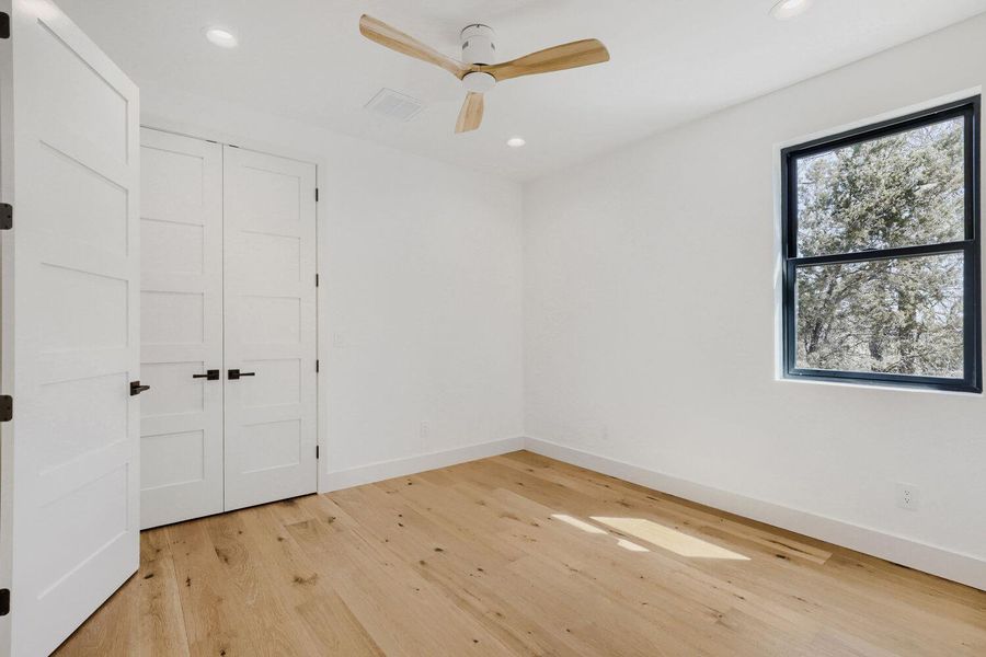 Unfurnished bedroom with light wood-type flooring, a closet, a ceiling fan, and recessed lighting Unfurnished bedroom with light wood-type flooring, a closet, a ceiling fan, and recessed lighting