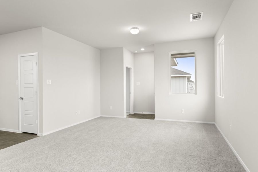 Image of a living room with cream walls, light gray carpeting, windows and white trim
