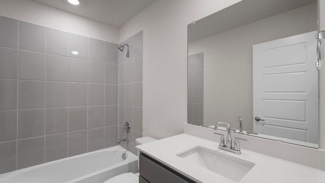 Full bathroom featuring a single vanity with a white countertop and undermount sink, chrome faucet, and a large unframed mirror