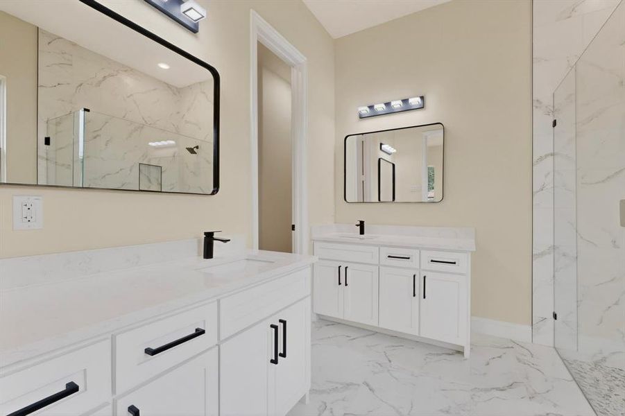 Dual vanity bathroom featuring white cabinetry, quartz countertops, and matte black fixtures
