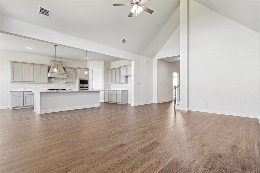 Unfurnished living room featuring high vaulted ceiling, ceiling fan, sink, and dark hardwood / wood-style flooring