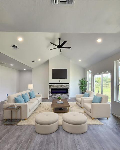 Living room featuring a fireplace, light wood-type flooring, vaulted ceiling, and ceiling fan. Virtual view