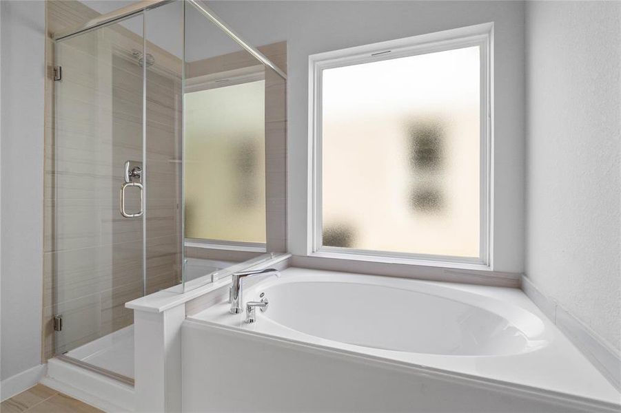 This master bathroom is definitely move-in ready! Featuring a framed walk-in shower with tile surround, separate garden tub for soaking after a long day!