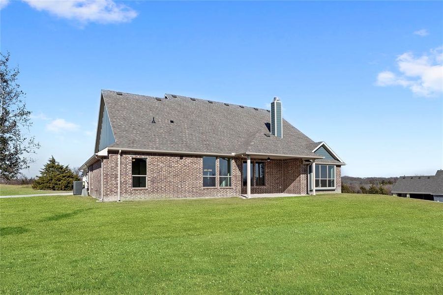 Rear view of property featuring cooling unit and a lawn