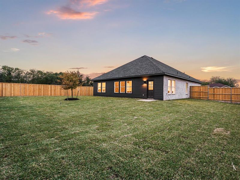 Back house at dusk featuring a yard