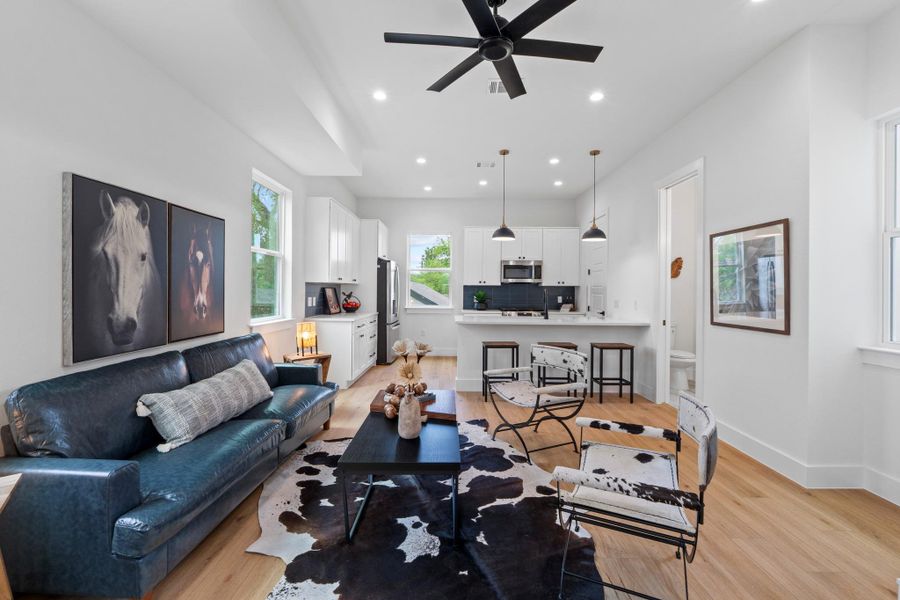 An open floor plan connects the living room to the modern kitchen featuring wood floors.