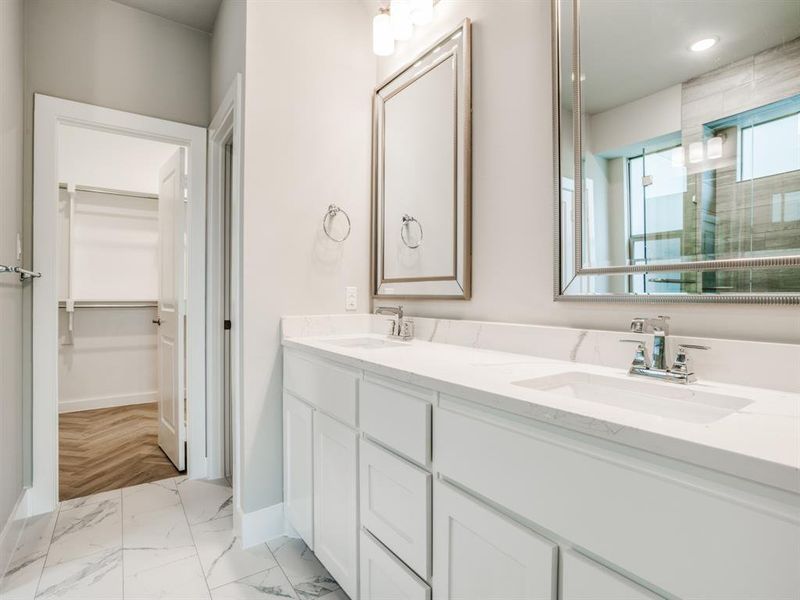 Bathroom with a spacious closet, double vanity, baseboards, and a sink