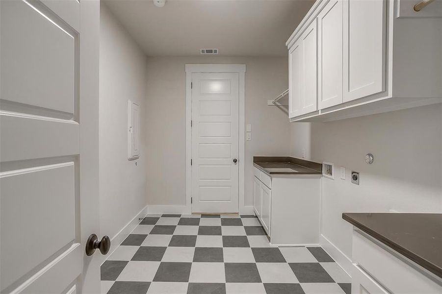 Clothes washing area with dark floors, visible vents, hookup for an electric dryer, baseboards, and cabinet space Clothes washing area with dark floors, visible vents, hookup for an electric dryer, baseboards, and cabinet space