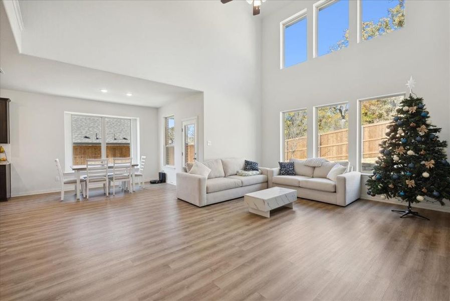 Living room featuring a high ceiling, light wood-type flooring, and ceiling fan