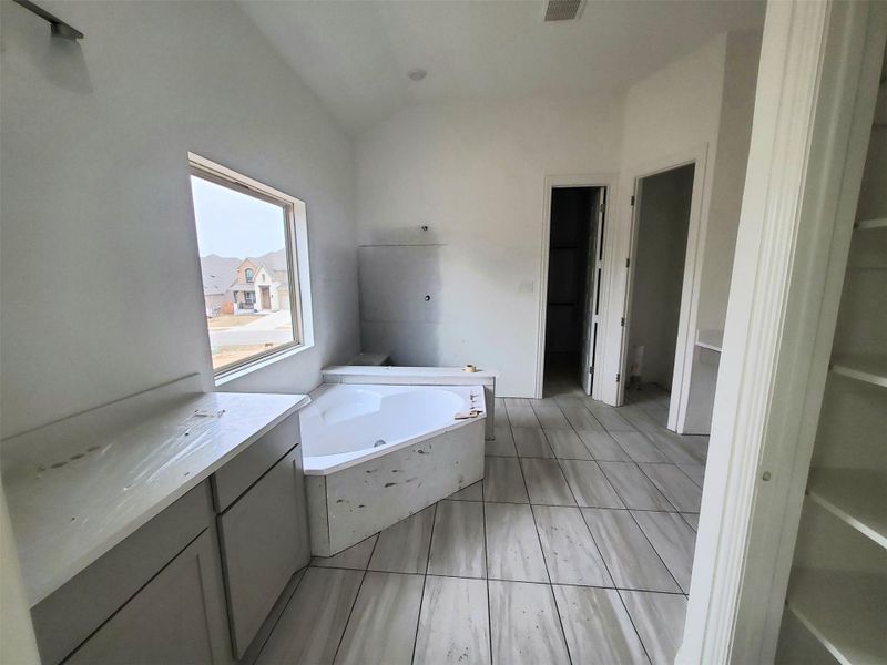 Full bathroom with lofted ceiling, a garden tub, and visible vents