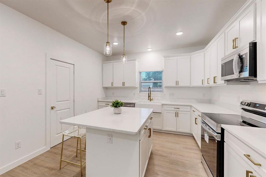 Kitchen with appliances with stainless steel finishes, light hardwood / wood-style flooring, a kitchen island, and sink