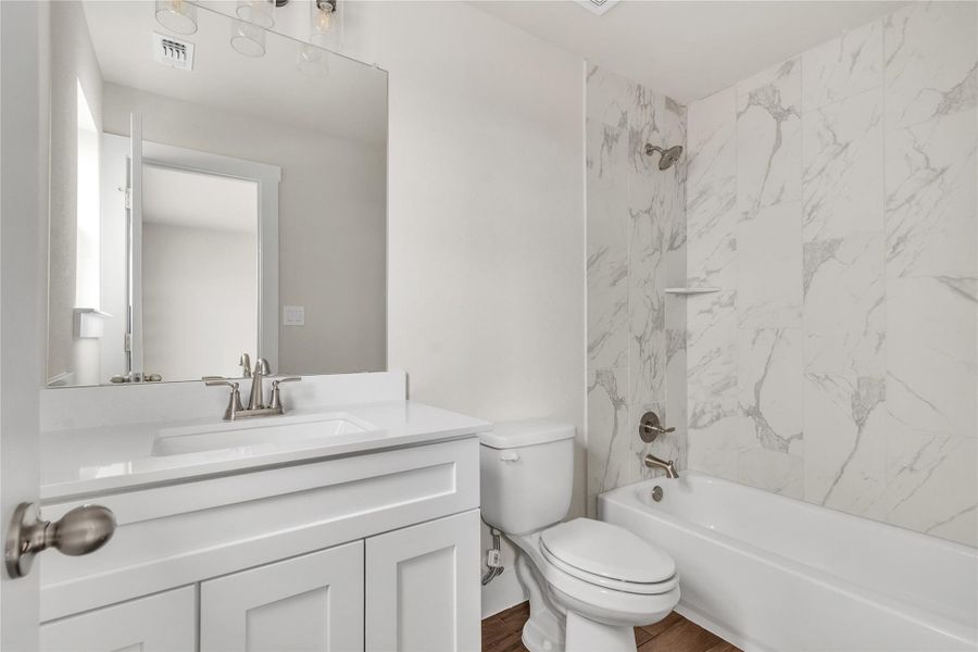 A well-appointed bathroom with a spacious vanity and elegant tiled shower-bathtub combination awaits.
